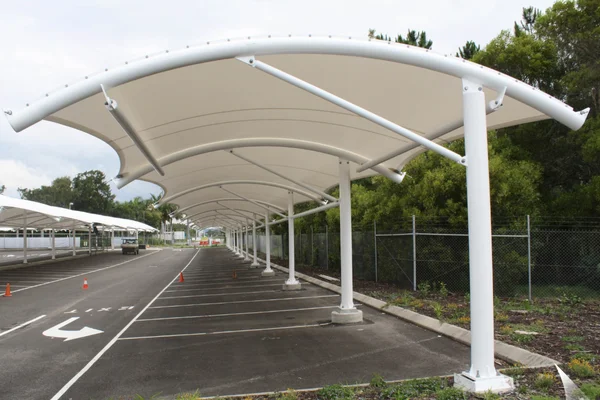 A modern car parking tensile structure by ShadeCo, showcasing a durable, stylish canopy installed over a parking lot, providing shade and protection for vehicles in a commercial or residential setting.
