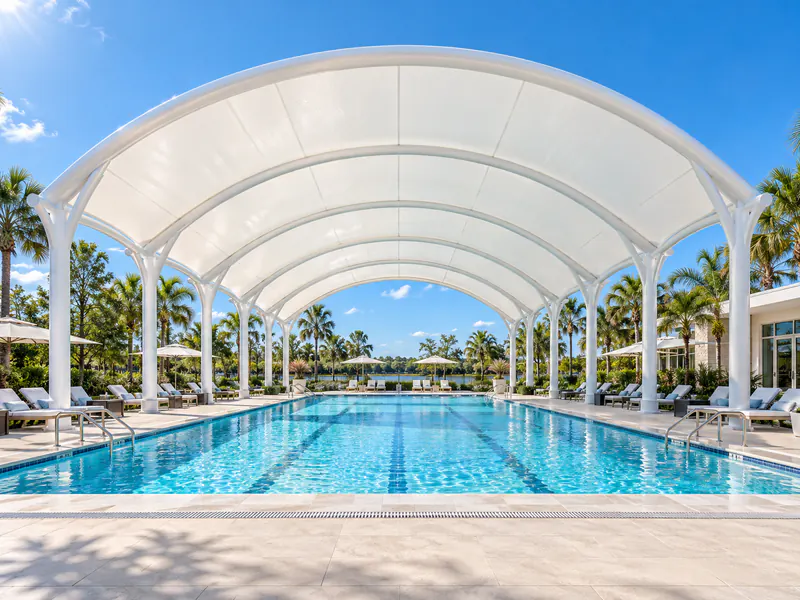 White arched tensile canopy covering a tropical swimming pool and poolside loungers