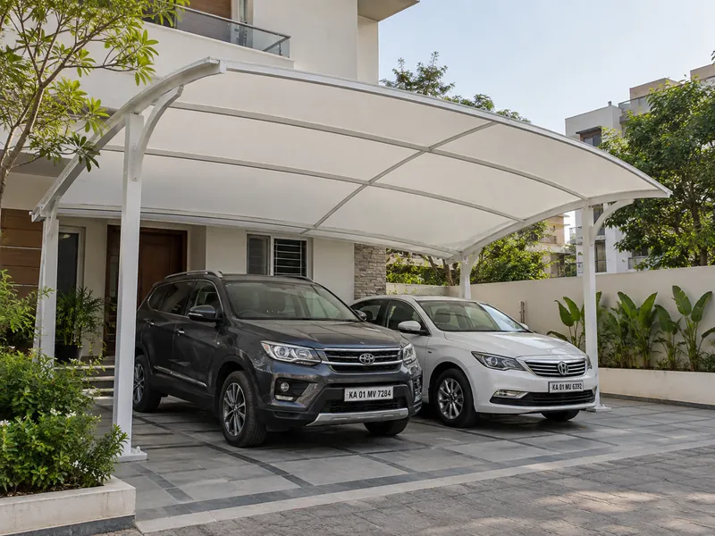 White curved fabric carport canopy on steel supports sheltering two cars beside a house