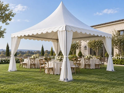 White pagoda tent with tied drapes and wedding dining tables on a lawn