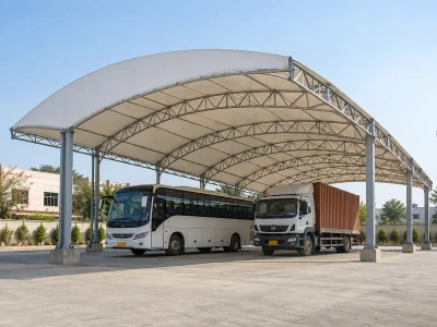 Tall parking shed with curved steel roof trusses sheltering a bus and a truck
