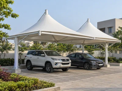 White conical parking canopies on steel frames above two cars