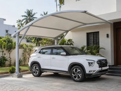 Single-car fabric parking canopy with braced steel supports beside a house