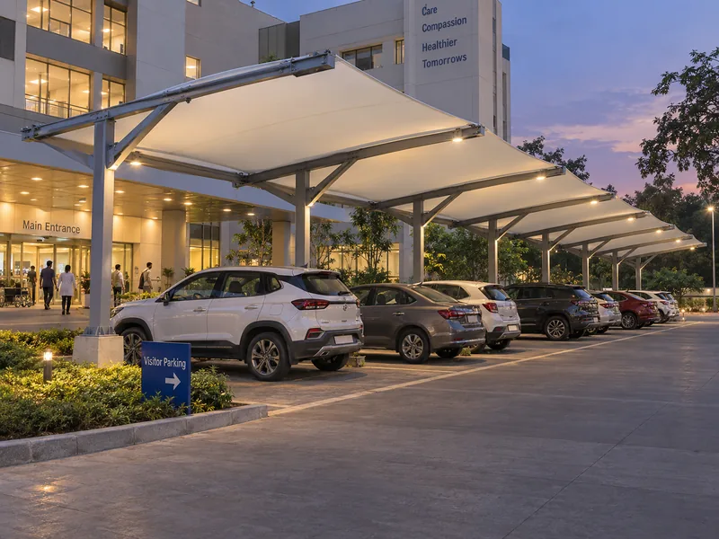 Lit commercial parking shade over visitor bays at a hospital entrance in the evening