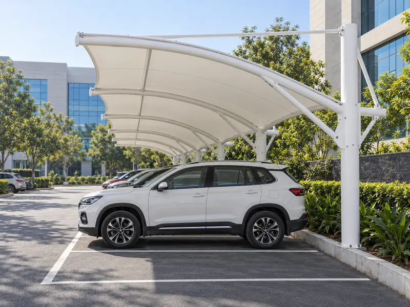 Side view of a white cantilever tensile parking canopy sheltering cars beside an office building