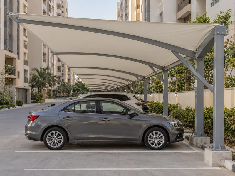 Long fabric parking shades over resident bays between apartment towers in a housing society