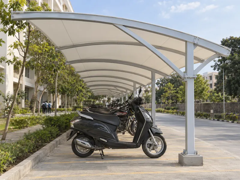 Long low parking shed over a single row of scooters and motorcycles at a college campus