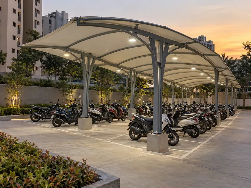 Back-to-back two wheeler parking shed with a curved roof and lights over two rows of bikes