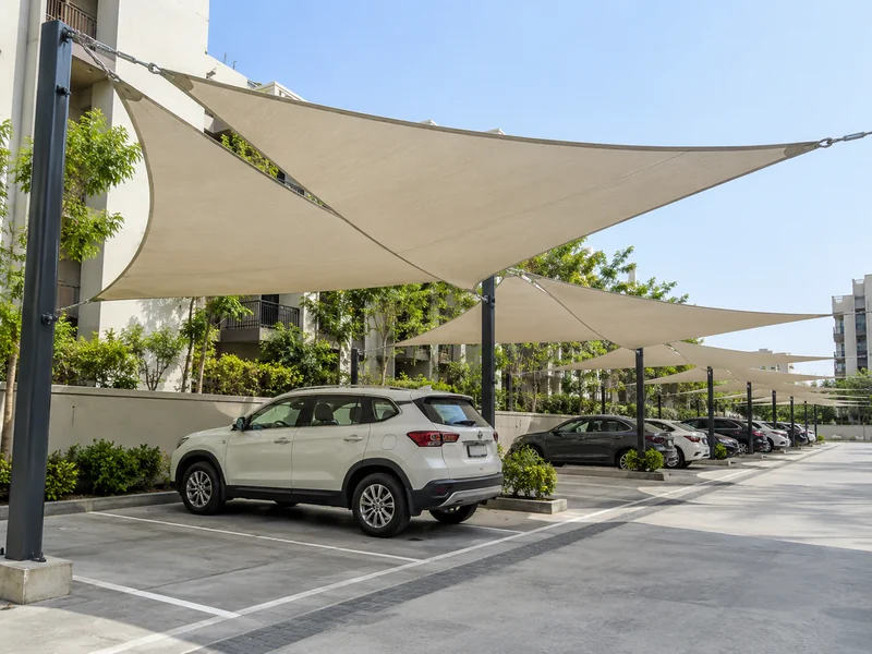 Row of overlapping shade sails over apartment visitor parking with posts set between the bays
