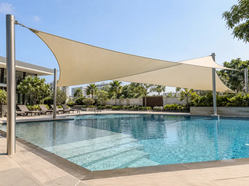 Shade sail over the shallow end of a club pool, with stainless corner fittings on a steel post