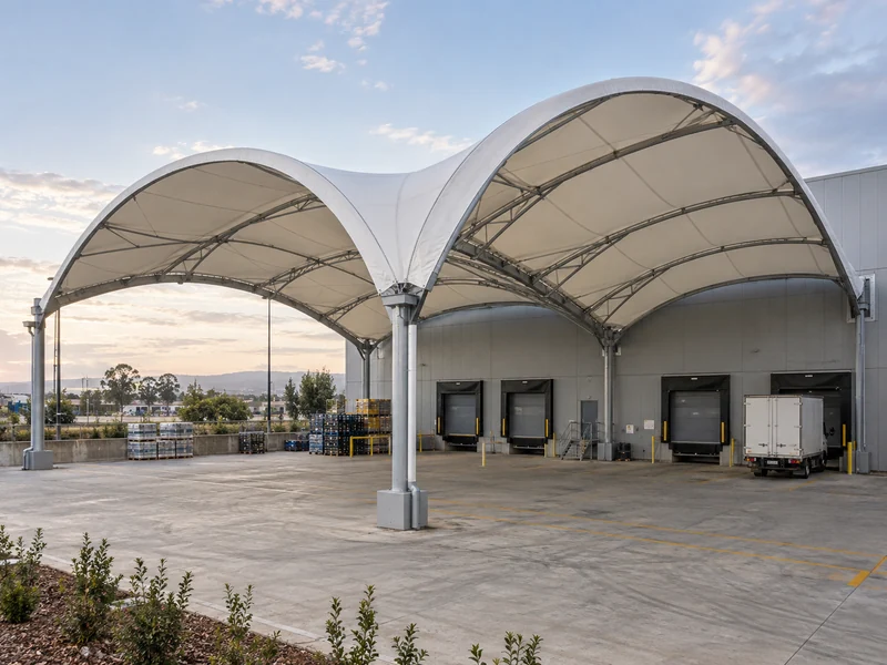 Two arched membrane bays side by side with a valley gutter over a factory loading yard