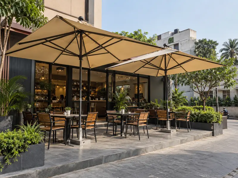 Two square fabric umbrellas in brand colours over outdoor tables at a small café front