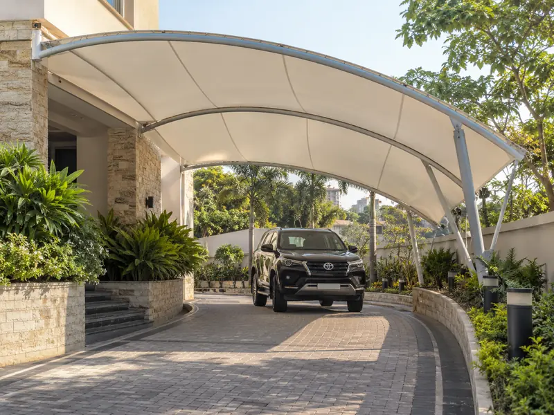 Arched membrane canopy over a curved home driveway with a car passing underneath