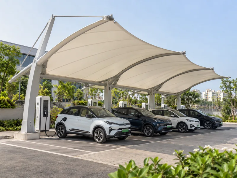 Cantilever fabric canopy over a row of EV chargers with electric cars plugged in below