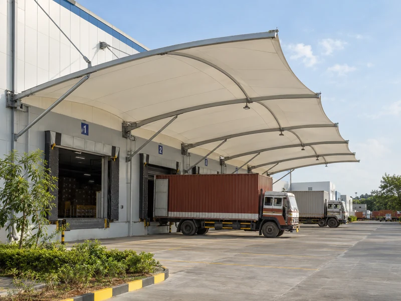 Wall-mounted fabric canopy over warehouse loading docks with trucks reversed up to the dock doors