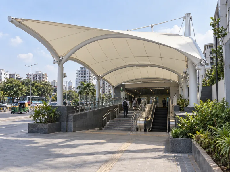 Curved fabric canopy over a metro station entry staircase and escalator on a city street