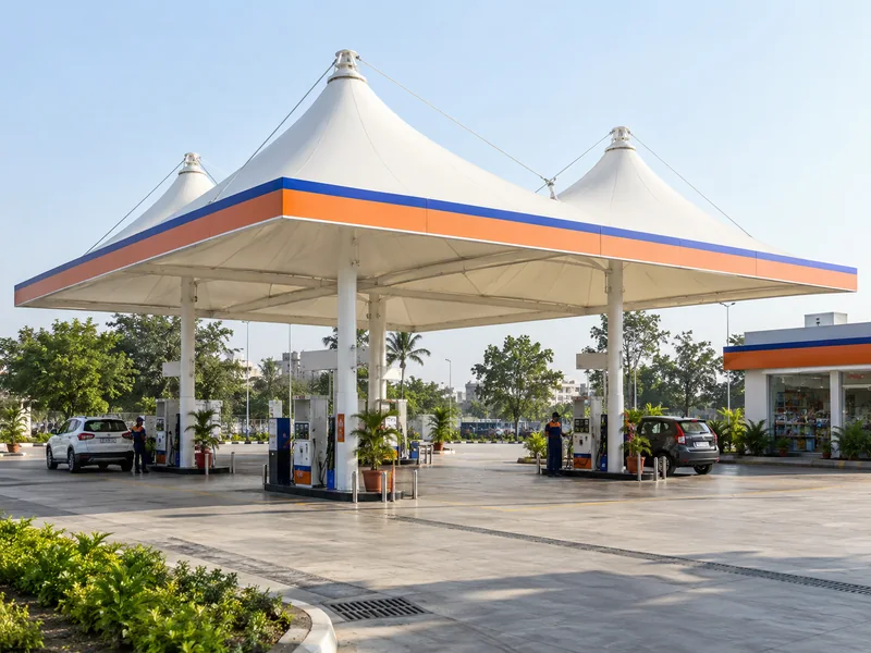 White peaked fabric canopy over fuel dispensers at a petrol pump with a coloured brand band at the edge