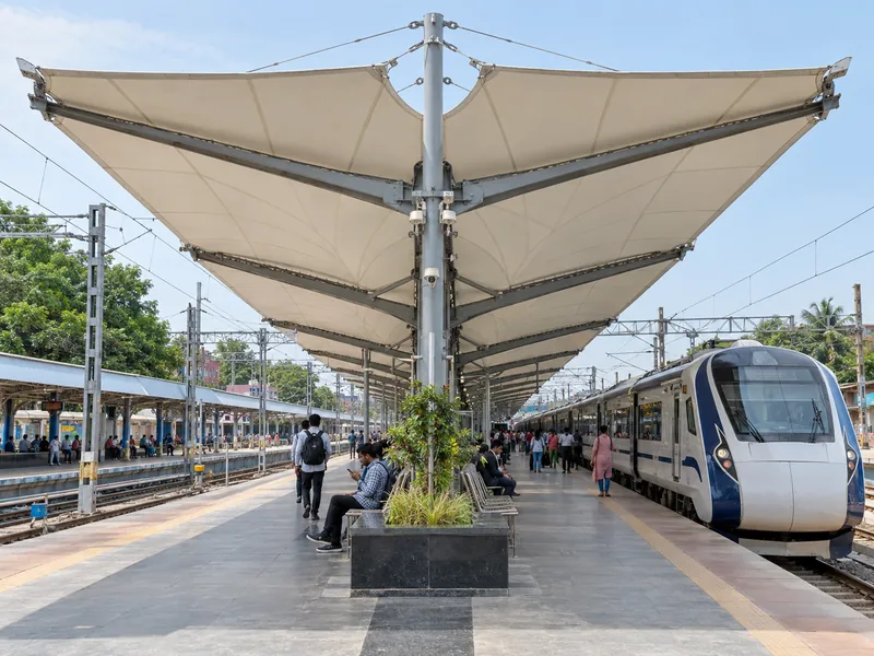 Island platform with a double cantilever membrane roof and a train waiting at the platform edge