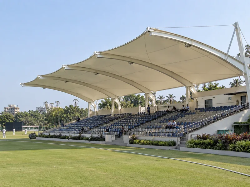 Cantilever fabric roof over a spectator gallery beside a cricket ground with no columns in front of the seats