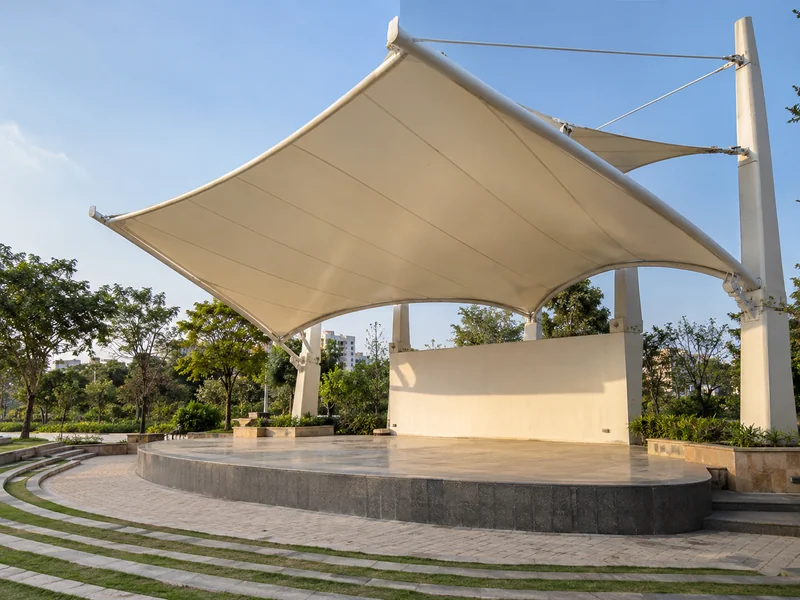 Cantilever membrane stage canopy in a park with columns behind the stage and an open front
