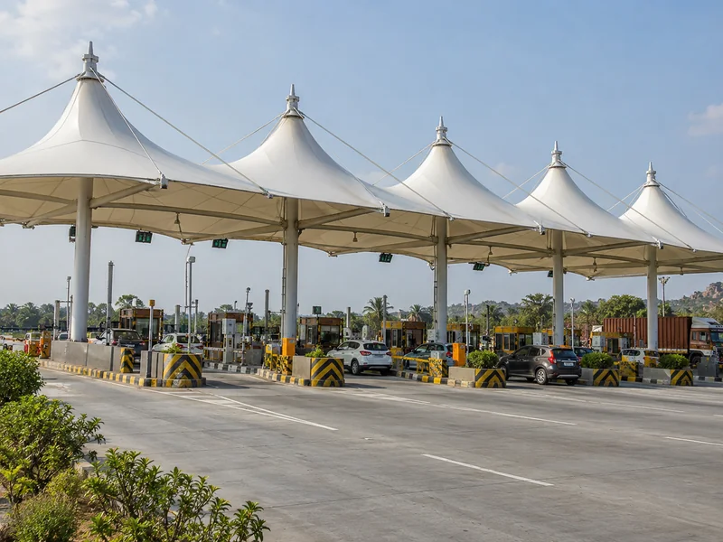Row of white peaked fabric canopies over highway toll lanes with columns on the lane islands