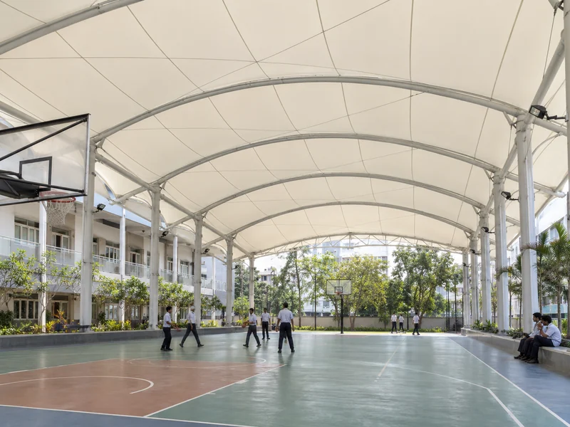 Underside of a light-transmitting membrane roof above a school play court, showing even shadow-free light