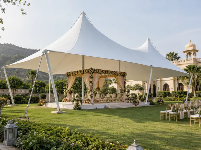 White peaked fabric canopy over a decorated mandap on a green wedding lawn