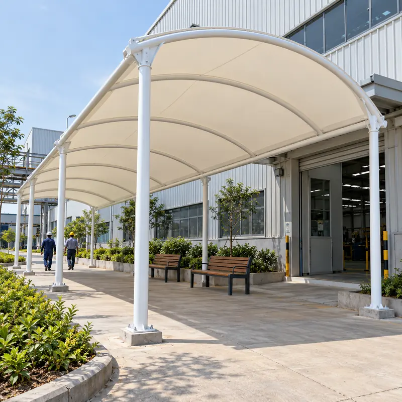 White curved-frame tensile canopy covering a factory staff walkway and outdoor seating area